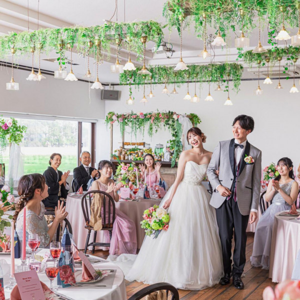 披露宴会場にて、ゲストに囲まれ、祝福されながら進む新郎新婦