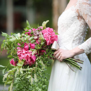 衣装とトータルコーディネートされた、花嫁の手元で鮮やかに咲き誇るブーケ。