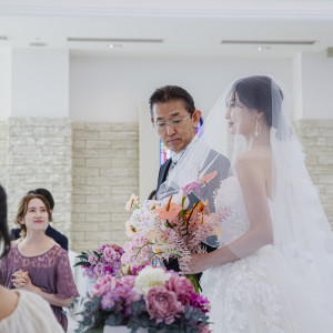 ガラスのバージンロードをお父様と一歩ずつ進むその瞬間。差し込む光とゲストの祝福に包まれ、これまでの感謝と新たな人生の一歩を感じる大切な時間です|ラヴィール岡山の写真(52126266)