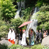 情緒溢れる庭園の小道を花嫁一行が歩く『参進の儀』。雄大に流れ落ちる滝を背に広がる情景は、まるで平安絵巻の様。