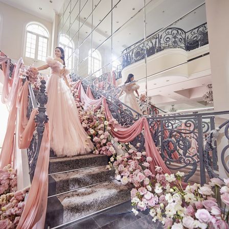淡く絶妙な色合いのドレスが、空間の装飾と美しくシンクロする。流れるようなフリルの美しさが、まるでドレスそのものが花咲いたかのような、可憐でドラマチックなワンシーン。|アートグレイス ウエディングシャトーの写真(37368828)