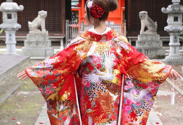 鮮やかな朱赤の地色に、翼を広げて舞い飛ぶ鶴と咲き誇る四季の花々が絢爛豪華に描かれた一着。