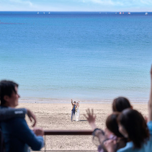 先輩花嫁に人気の砂浜からのサプライズ入場。ゲストもテラスへ出て一緒に楽しむ笑顔溢れる瞬間。|SCAPES THE SUITE（スケープスザスィート）の写真(32276858)