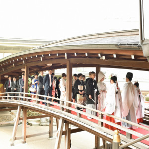 参列者全員で太鼓橋を渡って回廊から総檜造りの御社殿へと向かう参進は、写真も撮りやすく絵になります。また、屋根がついているので、当日の天候を気にせず安心して挙式に臨めます。|湯島天神の写真(16807256)
