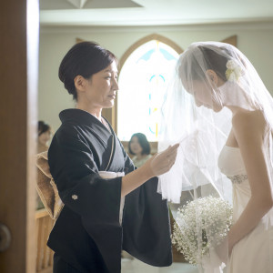 大切な方からのベールダウン。お母様から込み上げた思いが伝わる瞬間です。新婦様とお母様の入場、ベールダウン、そしてお父様へバトンタッチ。L字型の絆リレーとなっております。|ホテルクラウンパレス浜松の写真(41915263)