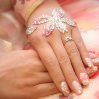 鮮やかな桜色のオーガンジー生地の上に重ねた手と手。新婦の左手には輝く婚約指輪と、和装に合わせたジュエルアートも。