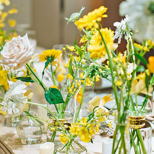 白と明るい黄色のお花を使用したデザイン。メインテーブルに小瓶を並べることで、明るいお花を使っても大人っぽいデザインにできます。お二人のご希望の内容をぜひご相談ください♪♪|ヴォヤージュ ドゥ ルミエール北谷リゾートの写真(35763382)