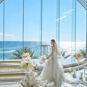 沖縄の砂浜をイメージした「サンドベージュ」を基調にしたチャペルは純白の花嫁姿を輝かせてくれます。サンセットタイムには、より幻想的な空間がおふたりを包みます。|ヴォヤージュ ドゥ ルミエール北谷リゾートの写真(23612488)