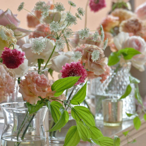ピンク系の花を使ったキュートなデザイン。小瓶を並べる流行りのスタイルでおしゃれなメインテーブル装花に。クロスも白系を選ぶことで可愛らしさの中に品のある空間を演出できます。|ヴォヤージュ ドゥ ルミエール北谷リゾートの写真(35762782)