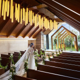 窓の向こうに広がる一面のガーデンビューと祭壇に降り注ぐ陽光が、清々しい開放感を生むチャペル。ウッド素材の落ち着いた香りに緊張もほぐれ、自然体のまま誓いの時を迎えられる。