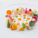新鮮な海の幸と旬野菜を丸く盛り付けた前菜。可愛いハーブや食用花を飾り華やかに。3種類のソースでお楽しみください。