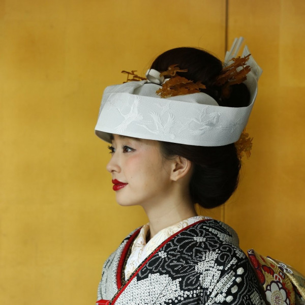 総絞りの黒の引き振袖と文金高島田で結った日本髪に角隠しが凛とした花嫁を演出