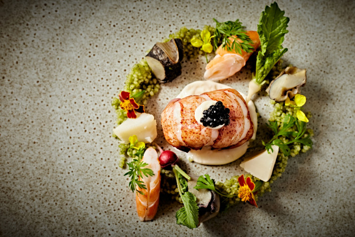 可愛く食用花と野菜の真ん中にオマール海老をあしらった一品。「食のあるべき姿の追求」がテーマ