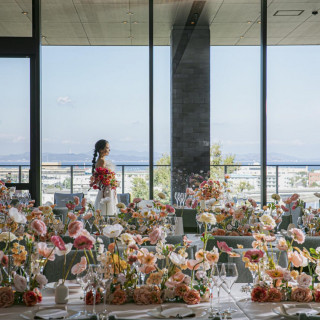 優しいピンクの花々に彩られたパーティ会場。
大きな窓の向こうには、高台からの景色が広がります
