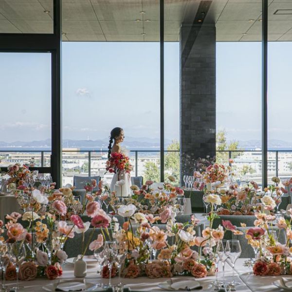 優しいピンクの花々に彩られたパーティ会場。
大きな窓の向こうには、高台からの景色が広がります