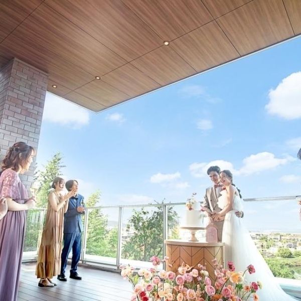 優しいピンクの花々に彩られたパーティ会場。
大きな窓の向こうには、高台からの景色が広がります