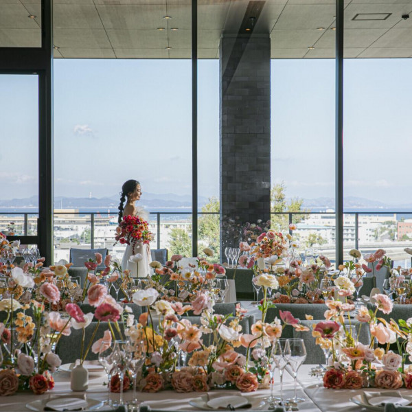 優しいピンクの花々に彩られたパーティ会場。
大きな窓の向こうには、高台からの景色が広がります