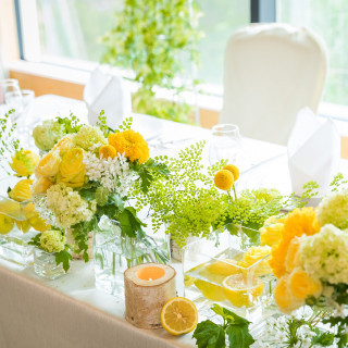 高砂席のおふたりをさらに輝かせるメインテーブル装花。自然光に映える黄×白×グリーンが爽やかで明るい仕上がりのナチュラル・コーディネート♪