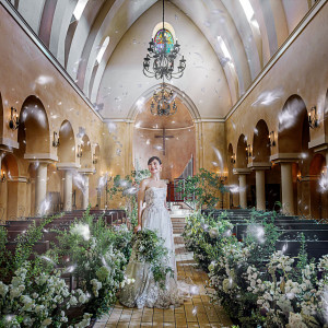 【フェザーシャワー】挙式クライマックスで純白のフェザーシャワーが舞い降りる。自然光と緑豊かな装飾が、花嫁を幻想的に包み込み祝福する演出に|アネーリ大宮（旧：ヴィラ・デ・マリアージュさいたま）の写真(55281061)