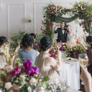 新郎新婦とゲスト全員での乾杯。背景には、華やかなパーティが始まる華やかなオープニング