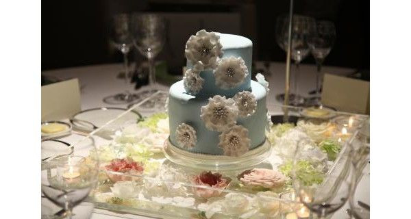 「純潔」を表すサムシングブルーを採用した2段のウエディングケーキです。白と淡いブルーの組み合わせが花嫁の清廉さをより一層際立たせます。大ぶりの華やかな白い花は花びらのひだがフリルのように動きを感じさせます。まさに特別な日の華やかさにふさわしい品のあるケーキです。