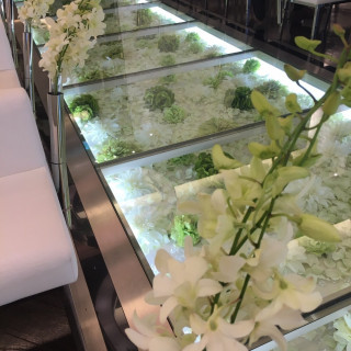 白い花や緑で埋められたガラス張りのバージンロードが特徴的です