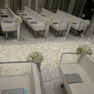 白基調のチャペル。バージンロードは白の花びらでいっぱい。