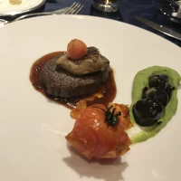 肉料理。付け合わせが黒ごま団子のような甘いもの。