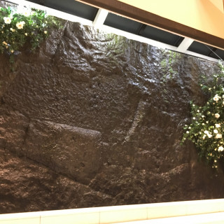 石の壁と流れる水、緑と花の画像です。