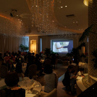 披露宴会場。プロフィールムービー上映中。