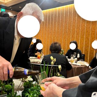 新婦の祖父からお酒をそそがれる新郎